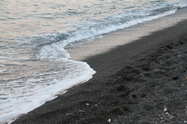 waves crashing against black sand
