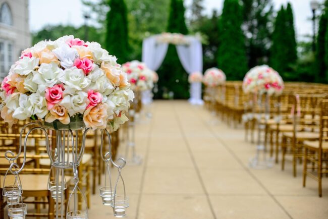 flower arrangement in the foreground, aisle all dressed up for a wedding in the background
